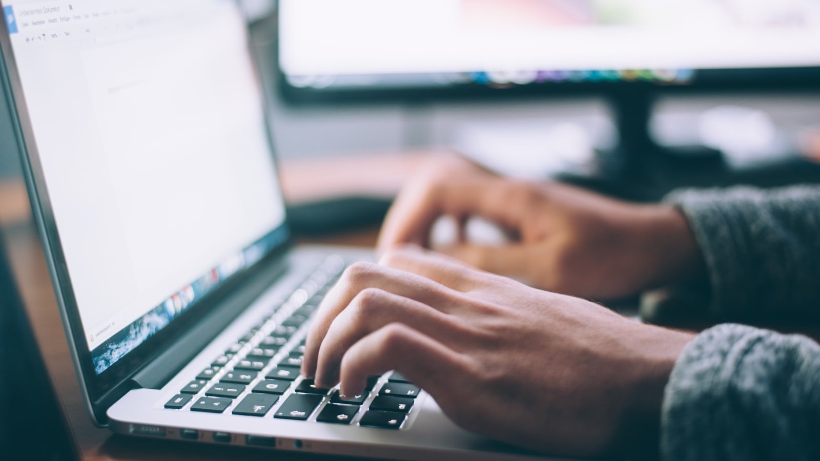 Dłonie piszące na laptopie przy biurku — praca, która zależy od baterii